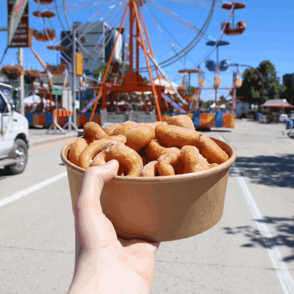 Arm outstretched holding container full of donuts